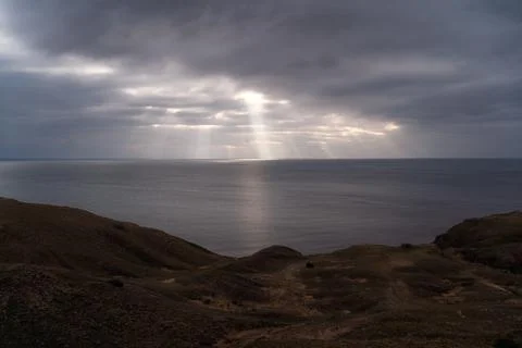 Sun rays make their way through dramatic clouds. Weather turns bad in the Stock Photos