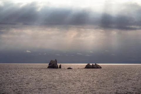 Sun rays make their way through dramatic clouds. Weather turns bad in the Stock Photos