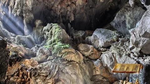 Sun rays moving across a mysterious cave with golden statue of Buddha Stock Footage 61792870