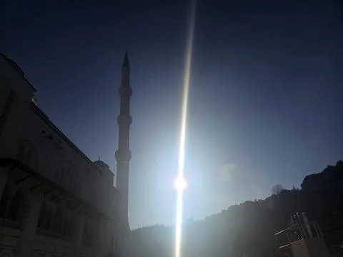 Sun rays over mosque minaret and domed building at dawn Foto stock