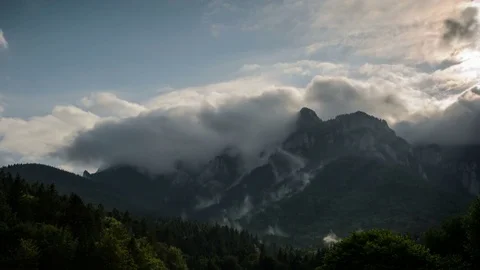 Sun rays pass through the clouds over the mountains at sunset. 4k timelapse. Stock Footage 77139902
