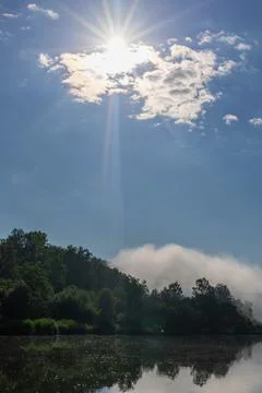 Sun rays passing through clouds above water surface Stock Photos