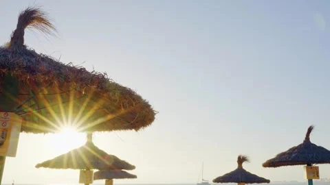 Sun rays peaking from beach umbrellas on the shore of Balearic Island Mallorca Stock Footage 282476254