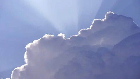 Sun rays peek out from behind a large white cumulus cloud in the sky Stock Footage 277251042