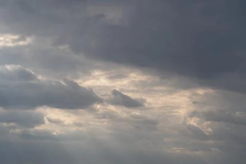 Sun rays pierce heavy clouds, warm glow and layered stratus produce cinemat.. Stock Photos