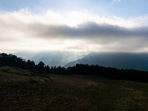 Sun rays piercing through clouds over Pyrenees mountains Stock Photos
