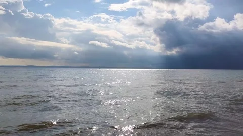 Sun Rays Piercing Through Dramatic Clouds Over Shimmering Sea Surface Video stock 332379777