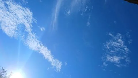 Sun Rays Piercing Through Scattered Clouds in a Blue Sky Stock Photos