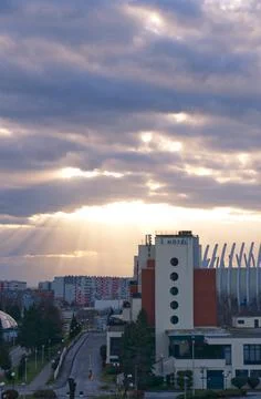 Sun rays piercing trough clouds at sundown, urban cityscape after a storm Stock Photos