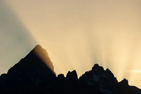 Sun rays reaching over the Grand Tetons at sunset Stock Photos