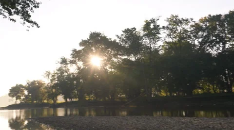 Sun rays seen through trees as sun rises along river Stock Footage 55145532