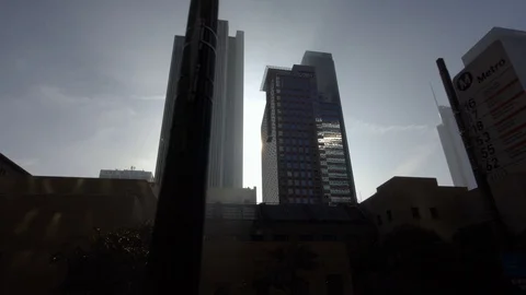 Sun rays shine between skyscrapers in downtown Los Angeles  street dolly shot Stock Footage 99117400