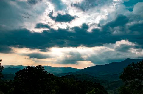Sun rays shine through a hole in black clouds after rain near Phang Nga Bay Foto stock