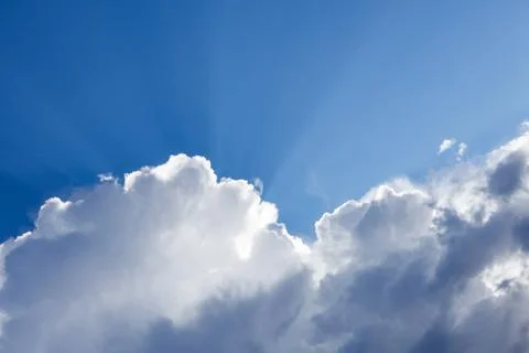 Sun rays shining behind cloud in the sky Stock Photos