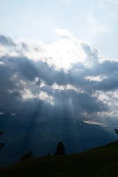 Sun rays shining trough the clouds in the mountains Stock Photos