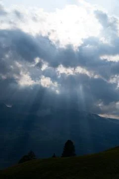 Sun rays shining trough the clouds in the mountains Stock Photos