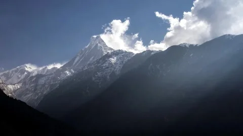 Sun rays shooting throuhg clouds over Mardi Himal ridge with Machapuchare Stock Footage 261809613
