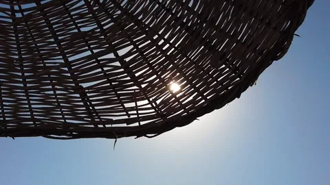Sun, rays of sun, sunlight shine through wicker beach umbrella from sun. Stock Footage 135272324