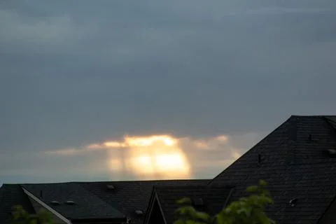 Sun rays at sunset over the roofline of a house Stock Photos