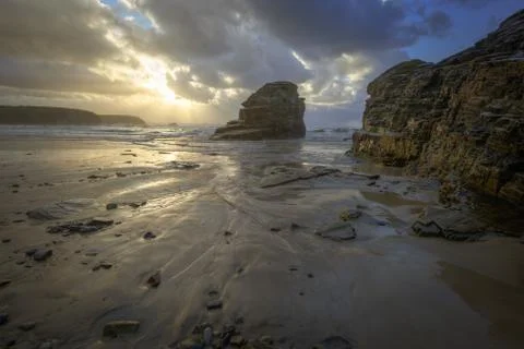 Sun rays of sunset seeps through the clouds on a beach Stock Photos