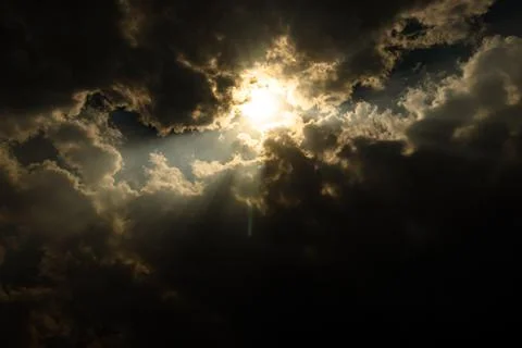 Sun rays through cloud patch at day dramatic scene Stock Photos