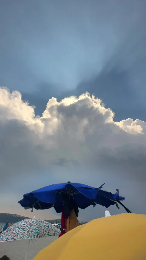 Sun rays through clouds over beach umbrellas at seaside. Vertical. Stock Footage 328974718