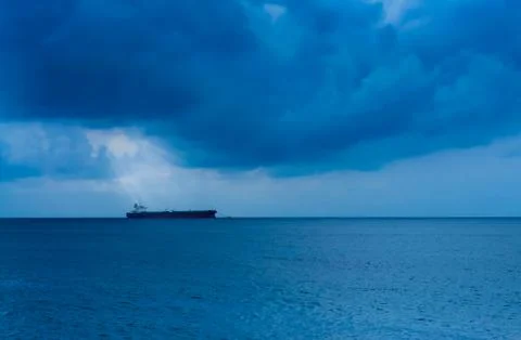 Sun rays through dark clouds over a ship Fotos Stock
