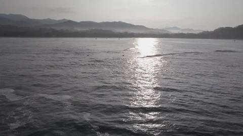 SUN REFLECS OFF WAVES, LAND BKGD | AERIAL, EXT, WIDE, TRKING FWD | 2398 | 4K Stock Footage 105256696