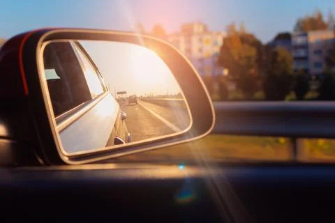The sun is reflected in the mirror, evening road, side rear view mirror Foto stock