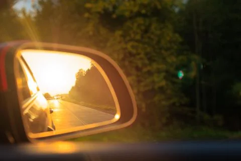 The sun is reflected in the mirror, evening road, side rear view mirror Foto stock