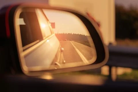 The sun is reflected in the mirror, evening road. Stock Photos