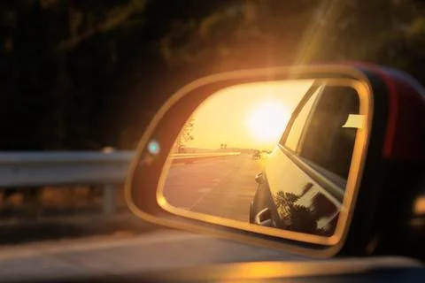 The sun is reflected in the mirror, evening road, side rear view mirror Foto stock