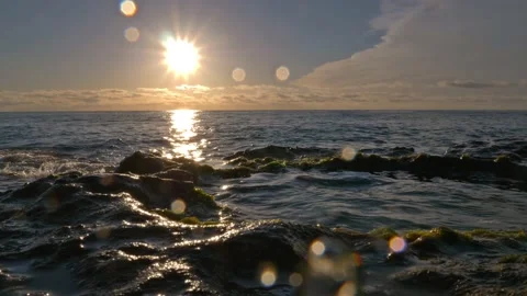 The sun is reflected on the rocky coast and drops of water hit the lens. Stock Footage 152855850