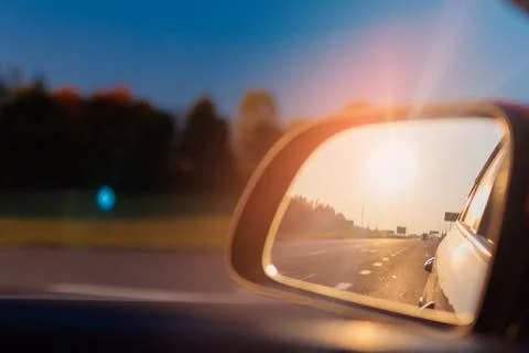 The sun is reflected in the side rear view mirror, evening road. Foto stock