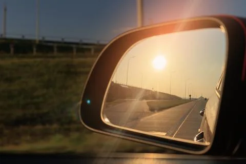 The sun is reflected in the side rear view mirror, evening road. Foto stock