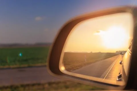 The sun is reflected in the side rear view mirror, evening road. Foto stock