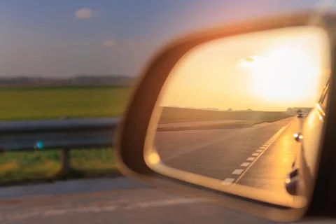 The sun is reflected in the side rear view mirror, evening road. Foto stock