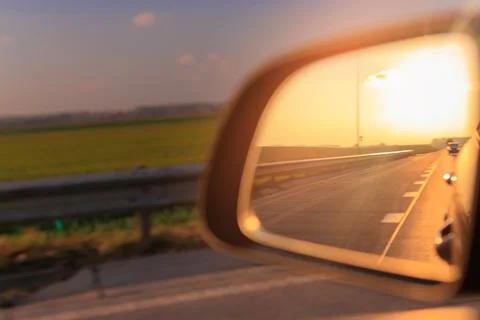 The sun is reflected in the side rear view mirror, evening road. Foto stock