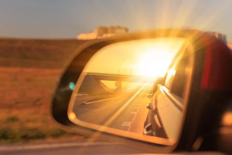 The sun is reflected in the side rear view mirror, evening road. 库存照片