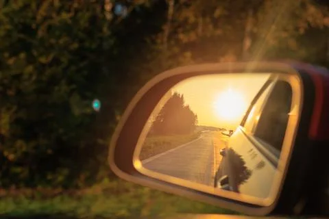 The sun is reflected in the side rear view mirror, evening road. Stock-Fotos