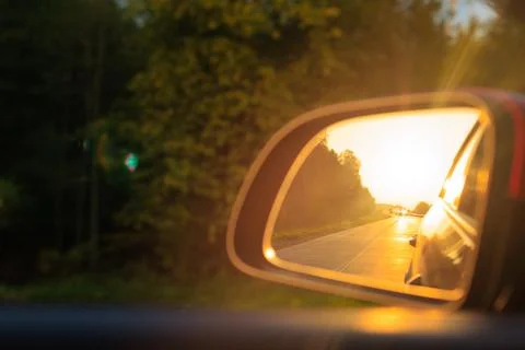 The sun is reflected in the side rear view mirror, evening road. Photos