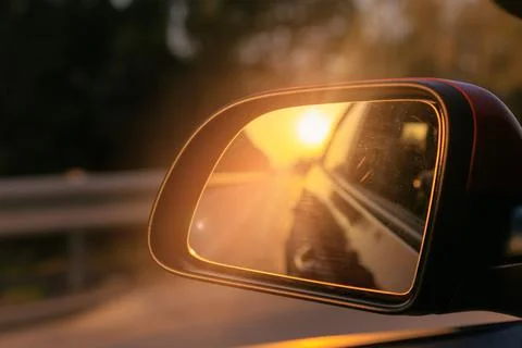 The sun is reflected in the side rear view mirror, evening road. Stock Photos
