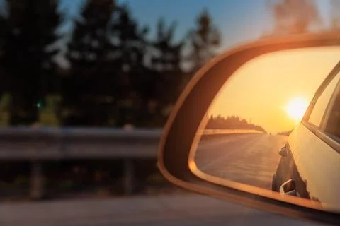 The sun is reflected in the side rear view mirror, evening road. Foto stock