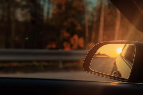 The sun is reflected in the side rear view mirror, evening road. Foto stock