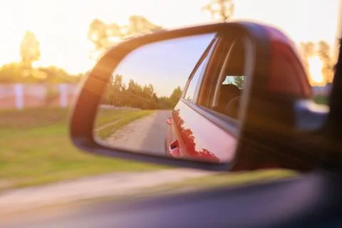 The sun is reflected in the side rear view mirror, evening road. Foto stock