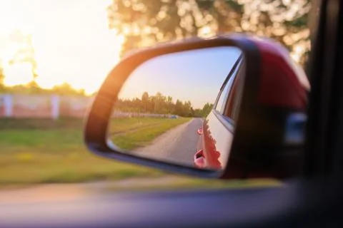 The sun is reflected in the side rear view mirror, evening road. 스톡 사진
