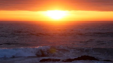 Sun reflected on surface of ocean at sunset as waves splash in foreground Stock Footage 108226925