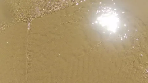 The sun reflected on the waves of the sea as it washes the shore Stock Footage 250009050