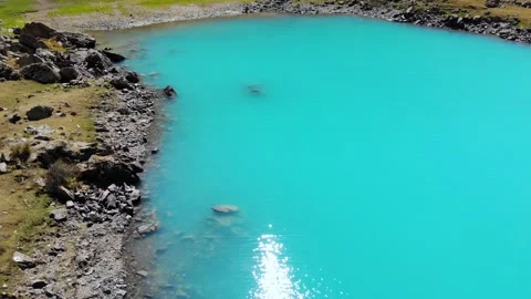 The sun is reflected in the waves of a turquoise alpine lake Stock Footage 232377862