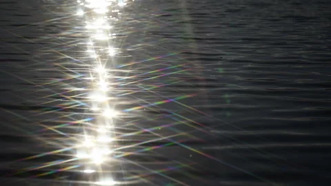 Sun reflection with rainbow lens flares shimmering on lake surface, slow motion Stock Footage 338237926